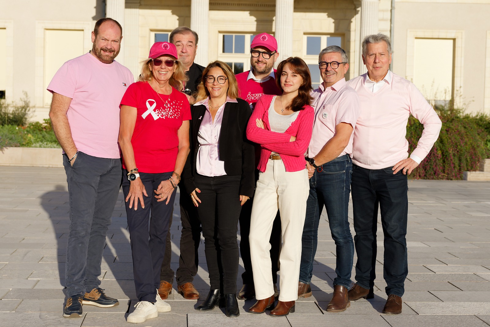 Photographie de groupe avec des vêtements et accessoires roses, en soutien à Octobre Rose